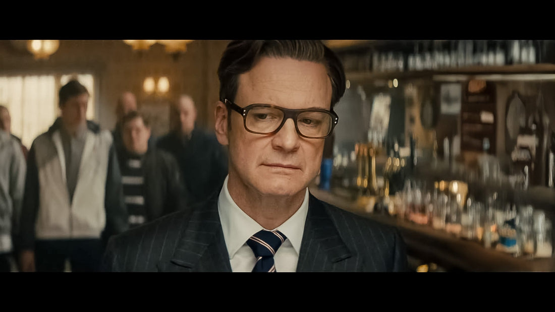 Colin Firth in a pinstripe suit and striped tie standing at a pub bar