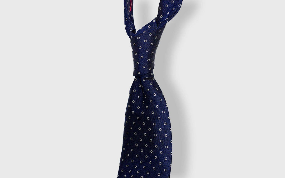 Navy silk tie with a white circle motif tied in a four-in-hand knot