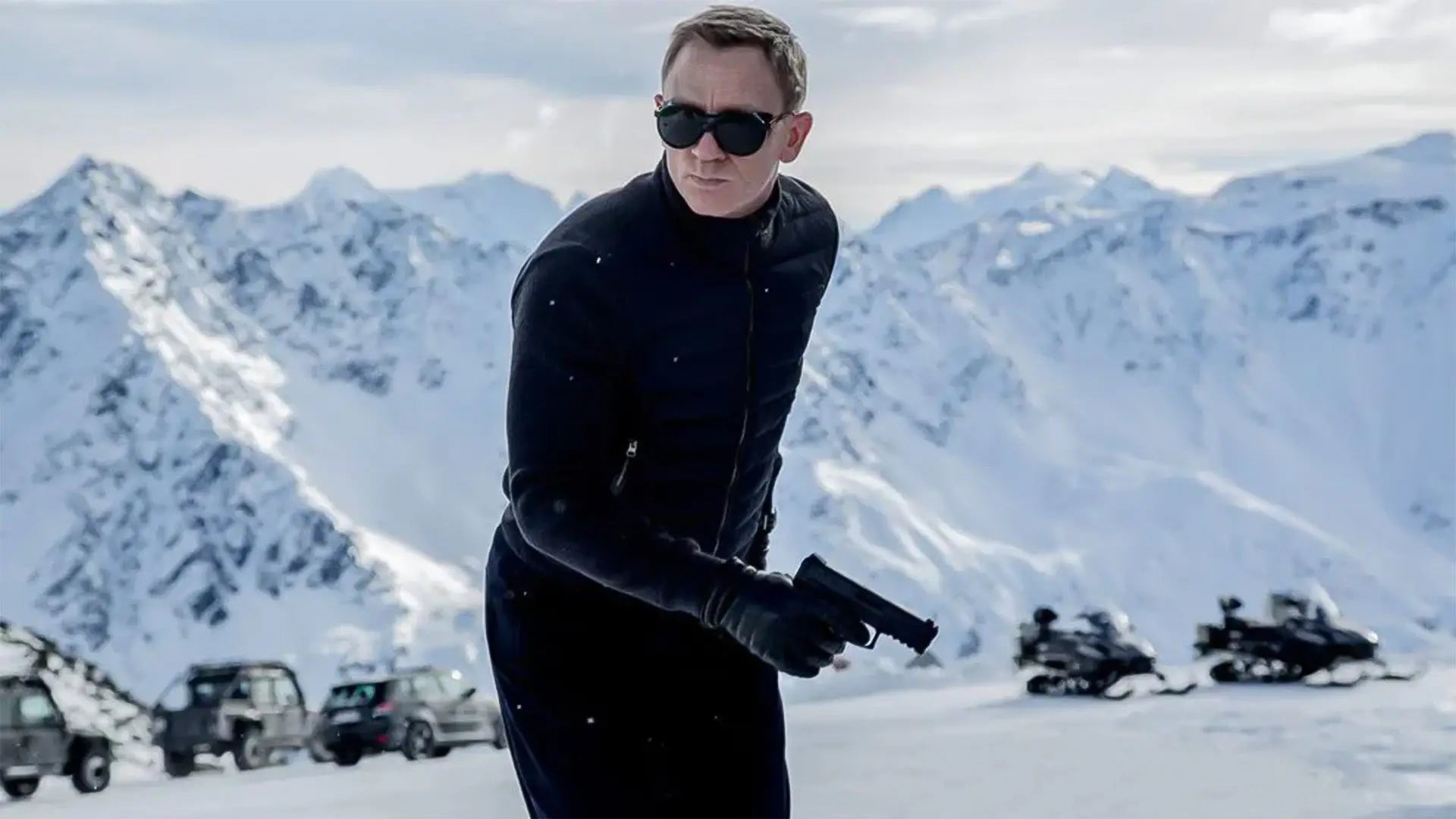 Daniel Craig as James Bond in a black quilted jacket and gloves on a snow-covered mountain