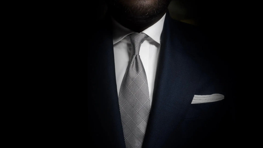 Navy suit worn with a white shirt, grey check tie and white pocket square