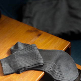 Grey dress socks folded on a wooden surface, highlighting ribbed design.