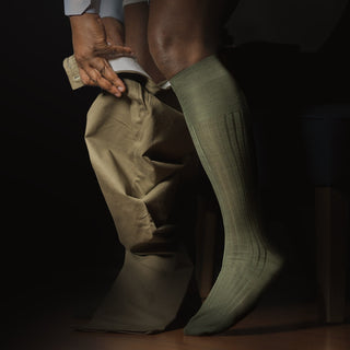 Person wearing olive green over the calf dress socks with formal attire.