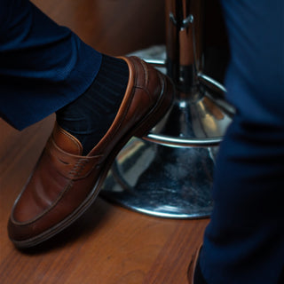 Dark blue dress socks paired with brown loafers and formal attire.