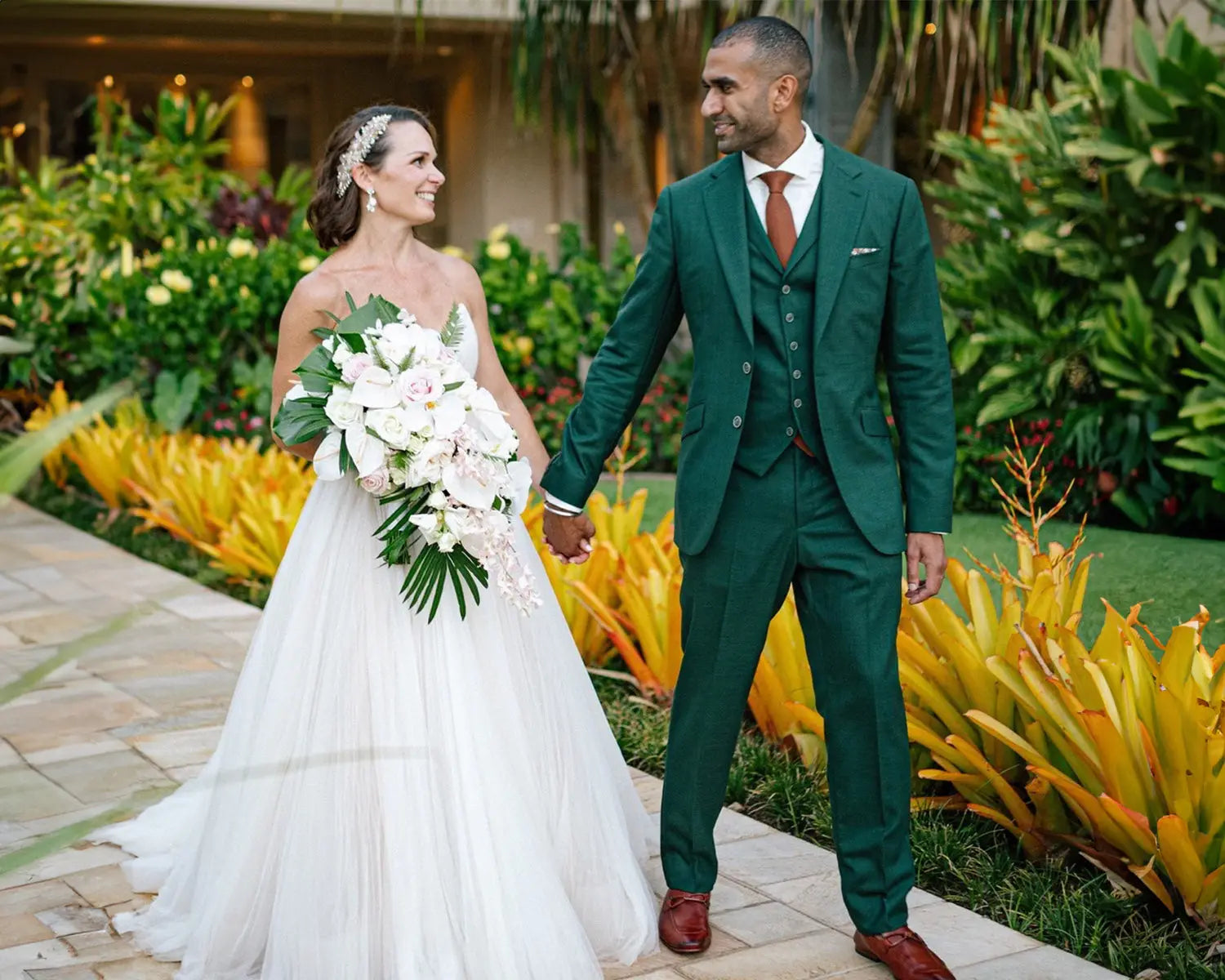 Newlyweds holding hands in wedding suits with dress shirts on their wedding day