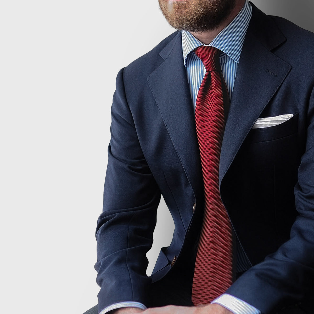 Burgundy Grenadine Tie worn with a navy suit and blue striped shirt, seated