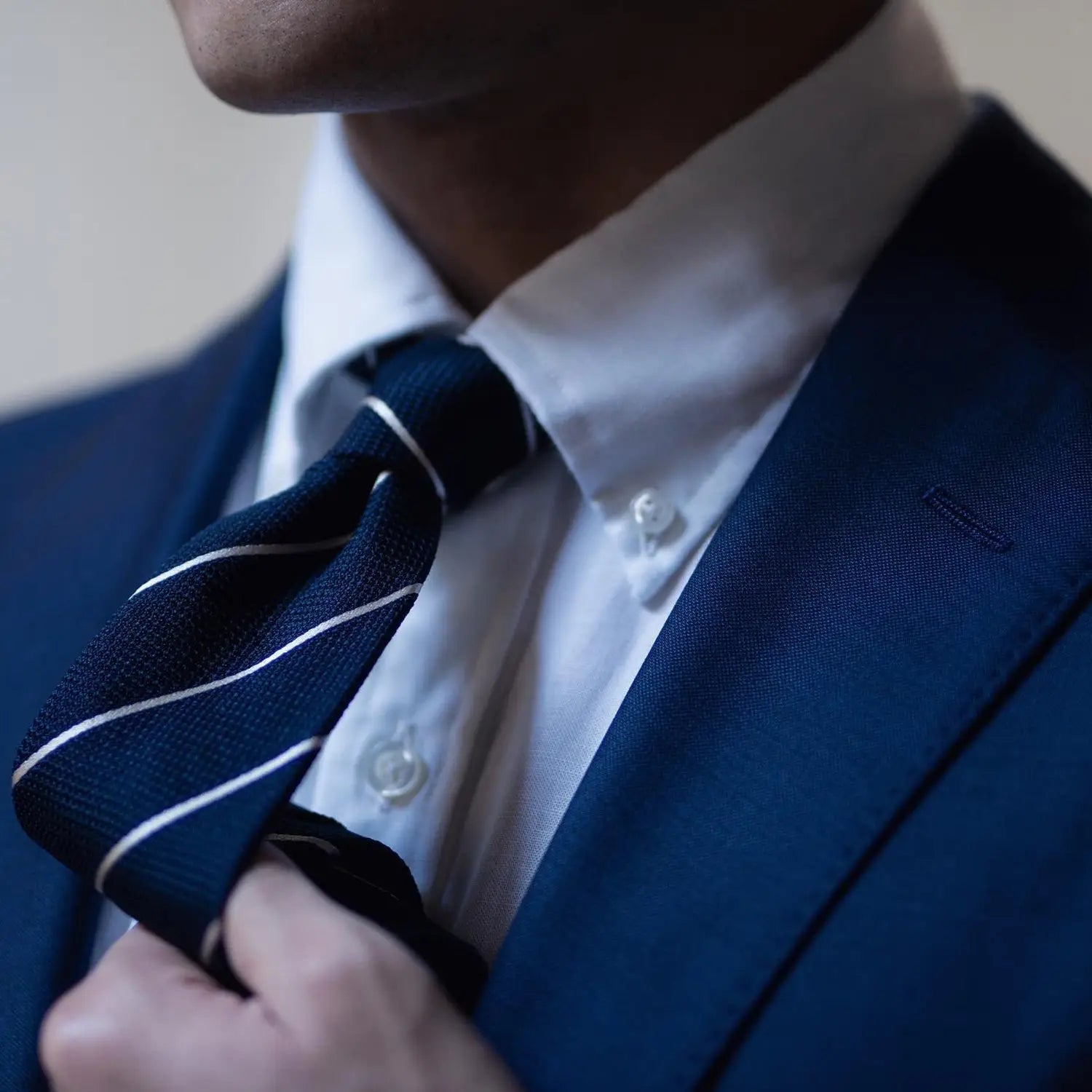 Blue suit with striped tie showcasing premium dress shirt fabrics for a sharp look
