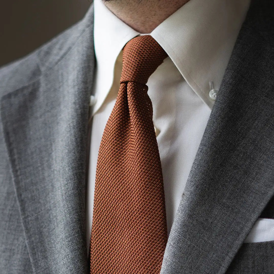 Gray suit with brown knit tie featuring a stylish touch for refined dressing