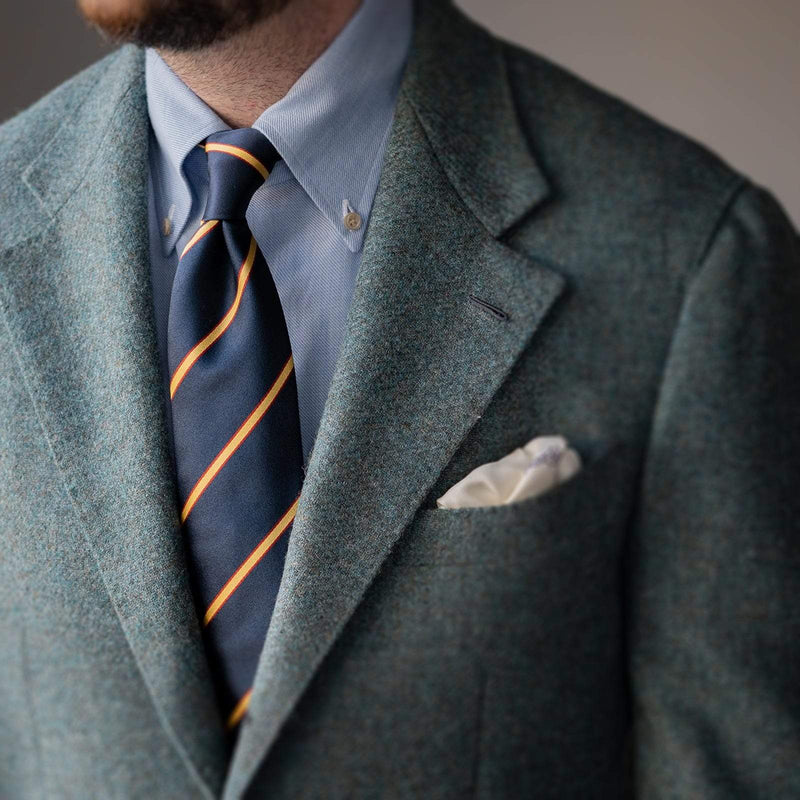 Gold and red striped navy blue tie styled with a suit, showcasing a polished formal look.