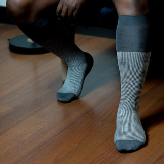 Person wearing grey houndstooth dress socks, styled for elegant comfort.