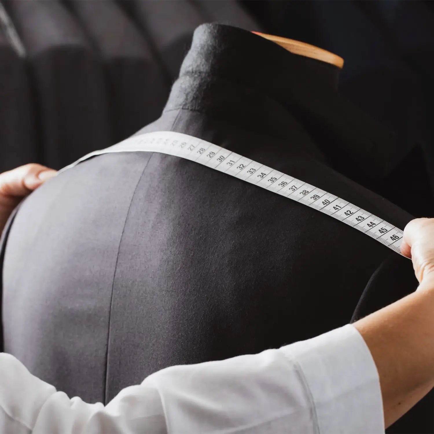 Black mannequin being measured for a wedding suit on wedding day in forest green grenadine fabric