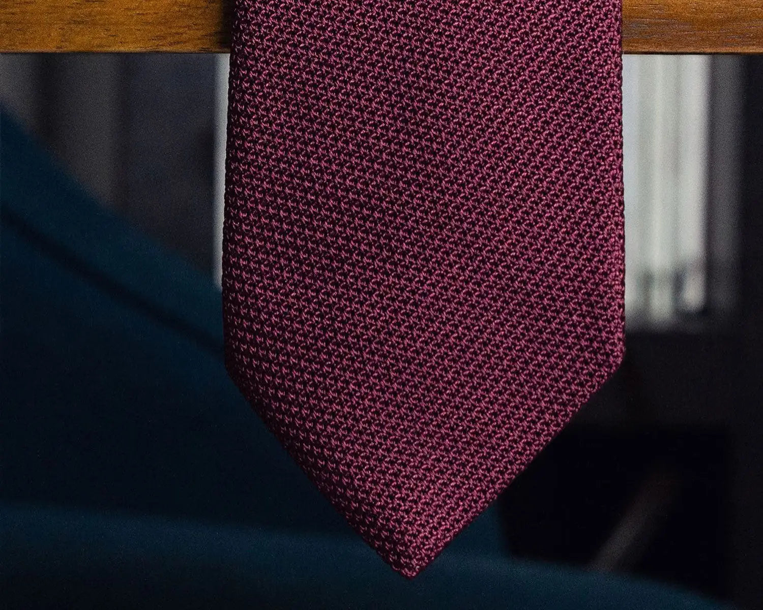 Burgundy knitted tie paired with grey suit and striped grenadine for a professional look