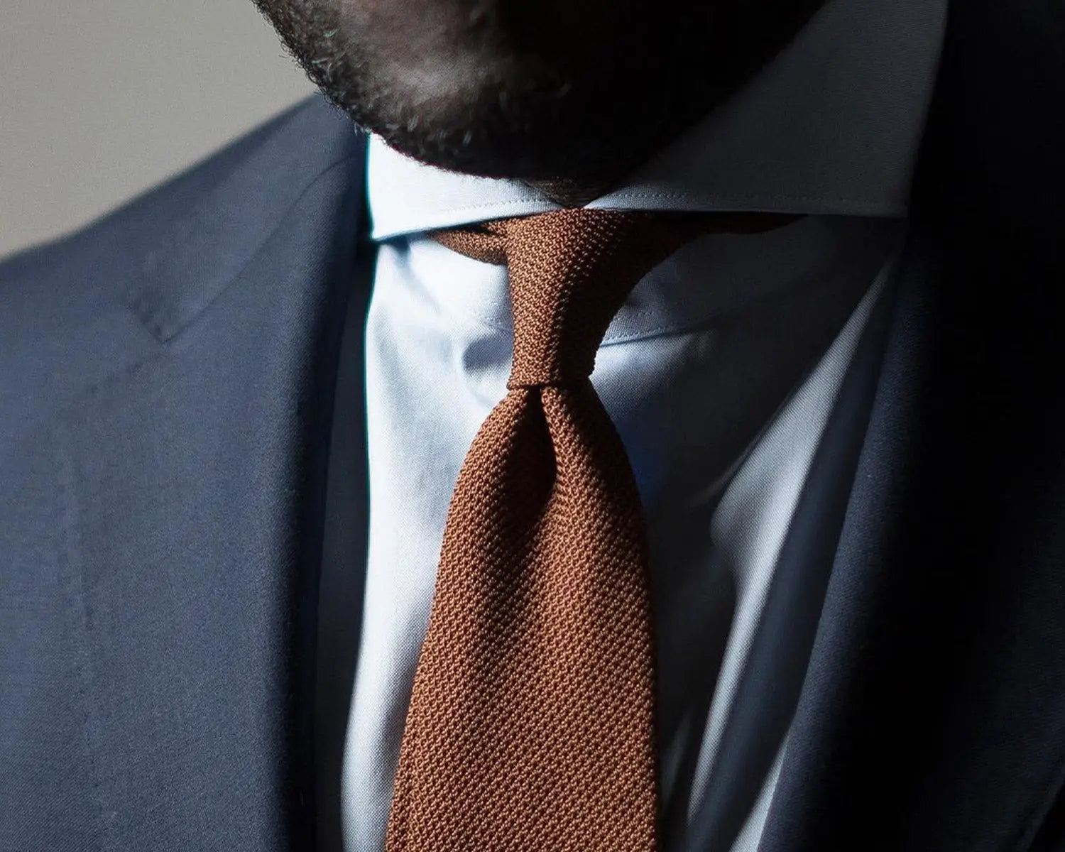 Brown knit tie paired with a grey suit, perfect for styling a striped grenadine tie