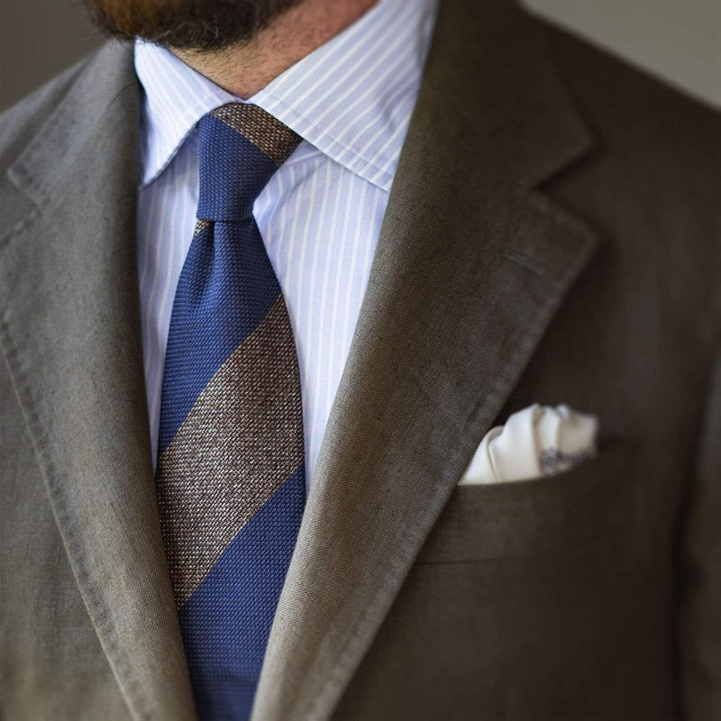 Man wearing a light brown and French blue block striped grenadine tie with a suit.