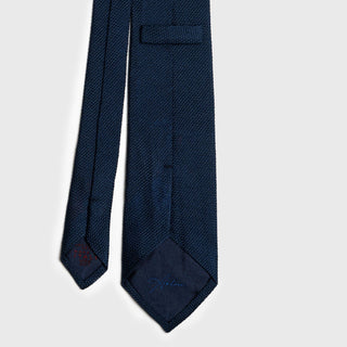 Close-up of navy grenadine tie with detailed stitching and branded lining.