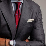 Red floral grenadine tie with a charcoal suit and white pocket square, close-up