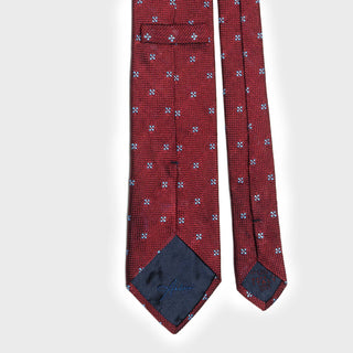 Back view of red floral grenadine tie with blue floral design and branded label.