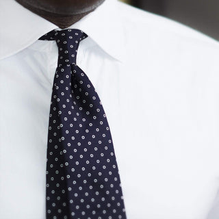 White ringed deep blue silk tie worn with a white shirt, exuding timeless elegance.