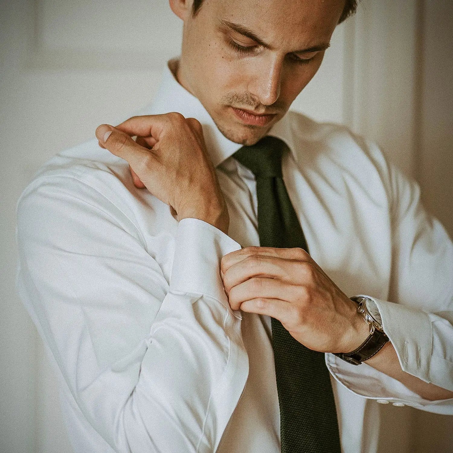 Man adjusting cuff on his forest green grenadine wedding suit for the wedding day