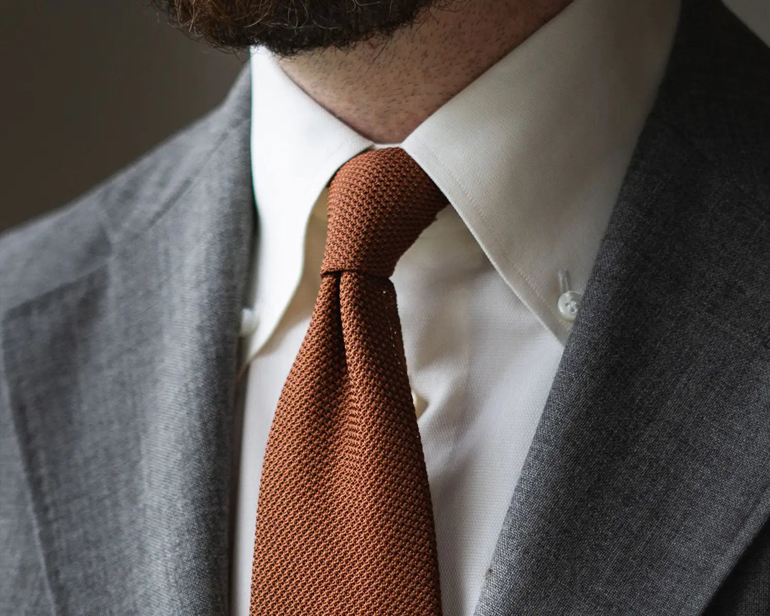 Gray suit with orange knit tie showcasing modern shirt collar styles for timeless fashion