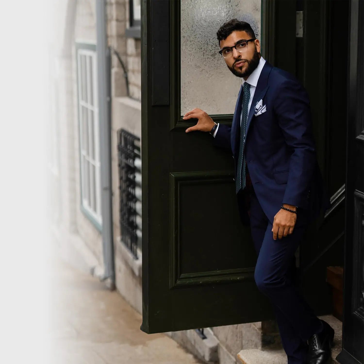 Man in a navy suit tying correctly or showing open collars for a professional look