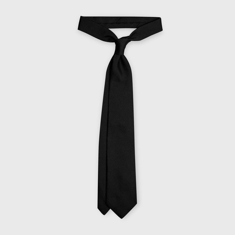 Black grenadine tie displayed in a tied knot, showcasing its elegant drape.