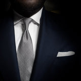 Black and white glen plaid tie with six-fold craftsmanship paired with a navy suit.