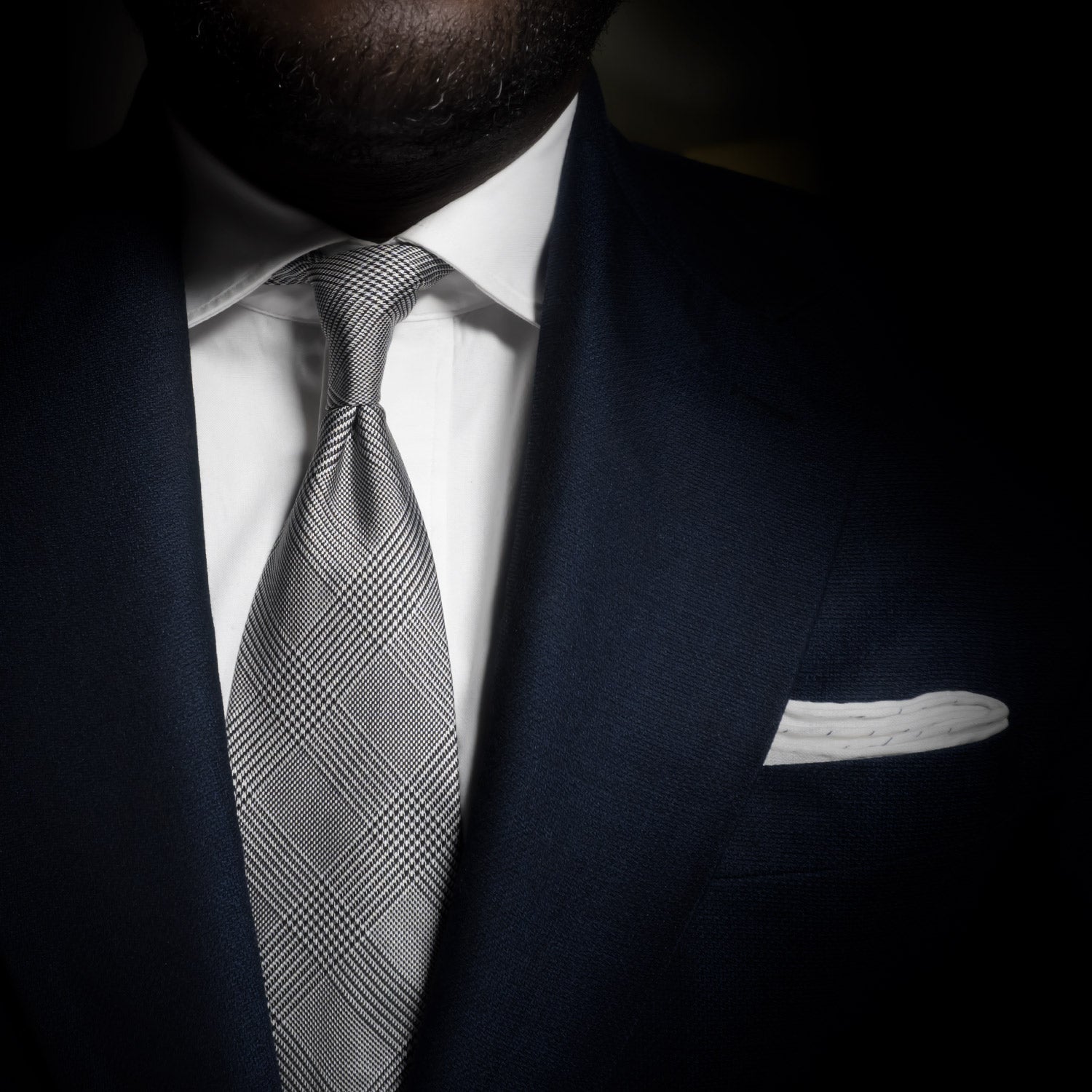 Black and white glen plaid tie with six-fold craftsmanship paired with a navy suit.