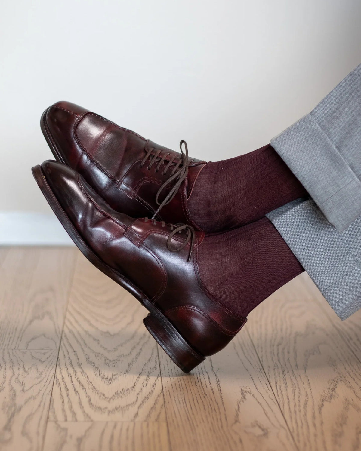 Burgundy over-the-calf dress socks with light grey trousers and oxblood derbies