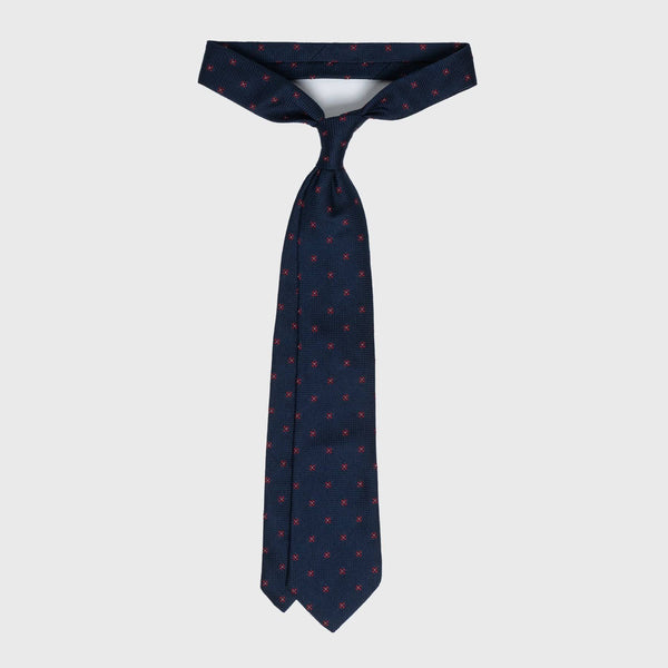 Dark blue floral grenadine tie with red flower pattern, displayed untied.