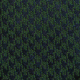 Navy blue and green houndstooth pattern on silk tie fabric.