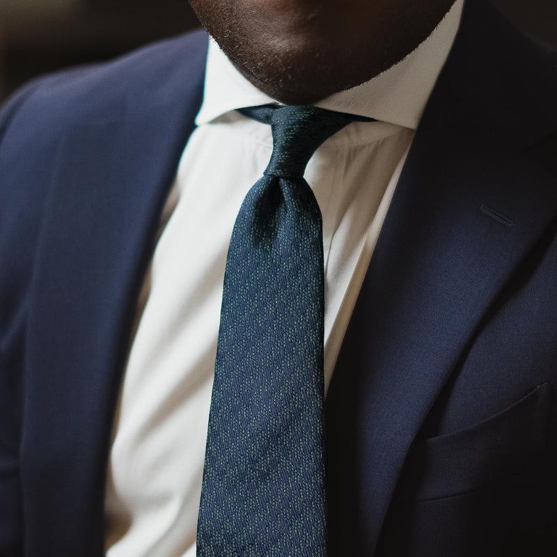 Green and navy blue houndstooth six-fold tie, handcrafted silk, worn with a navy suit.