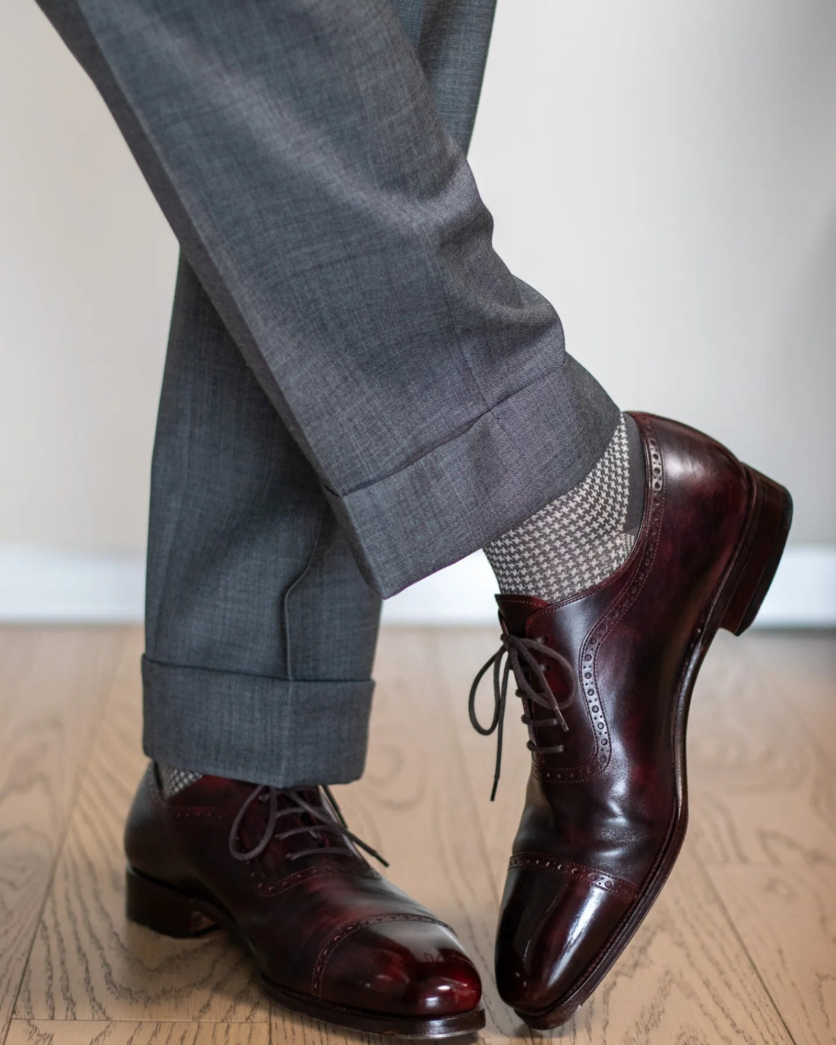 Grey houndstooth over-the-calf dress socks with grey trousers and burgundy cap-toe oxfords