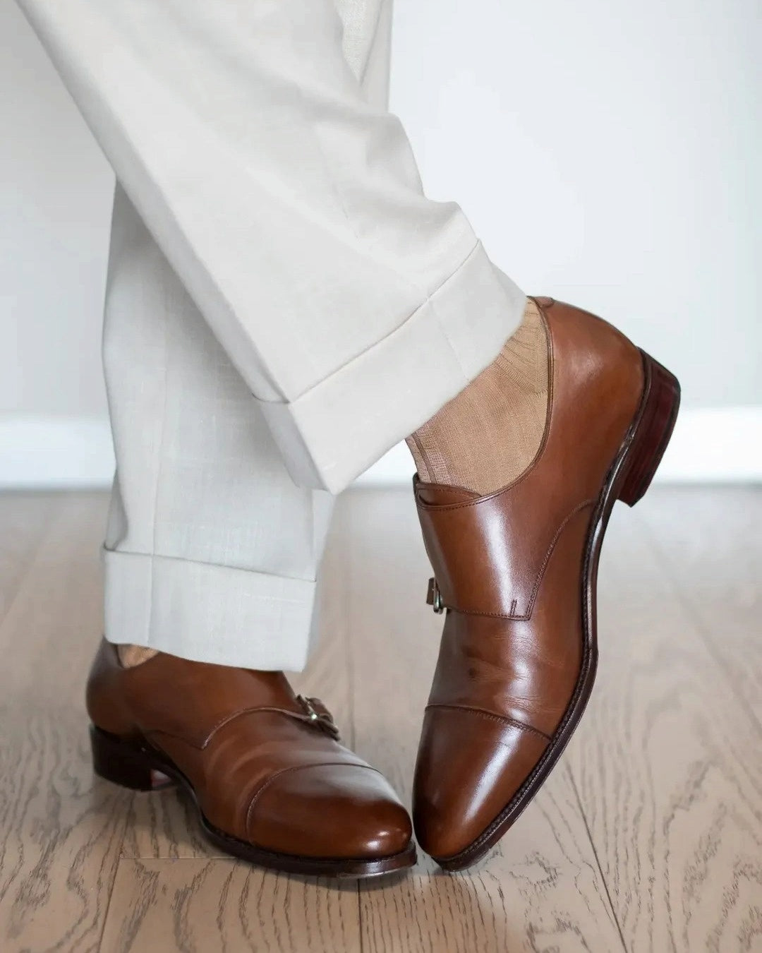 Light brown dress socks worn with cuffed cream trousers and brown monk straps