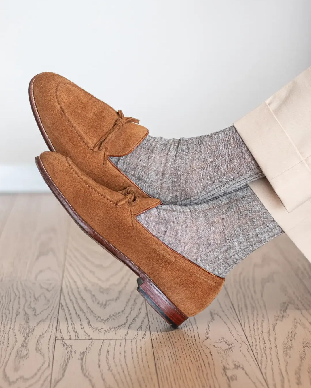Melange brown linen dress socks worn crossed at the ankle with brown suede loafers