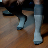 Grey houndstooth over-the-calf dress socks worn under a tailored trouser
