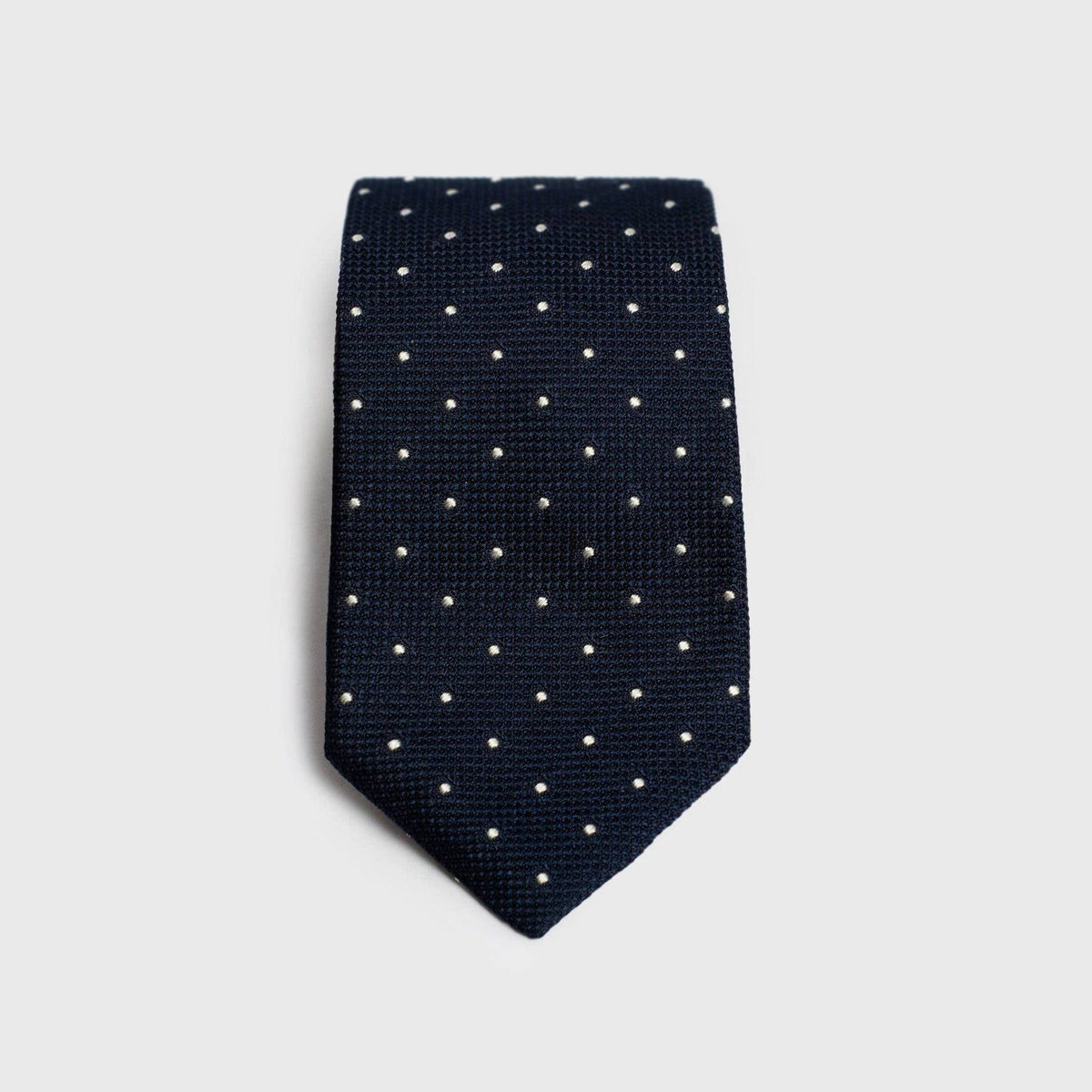 Navy dotted grenadine tie with a textured finish, folded for display.