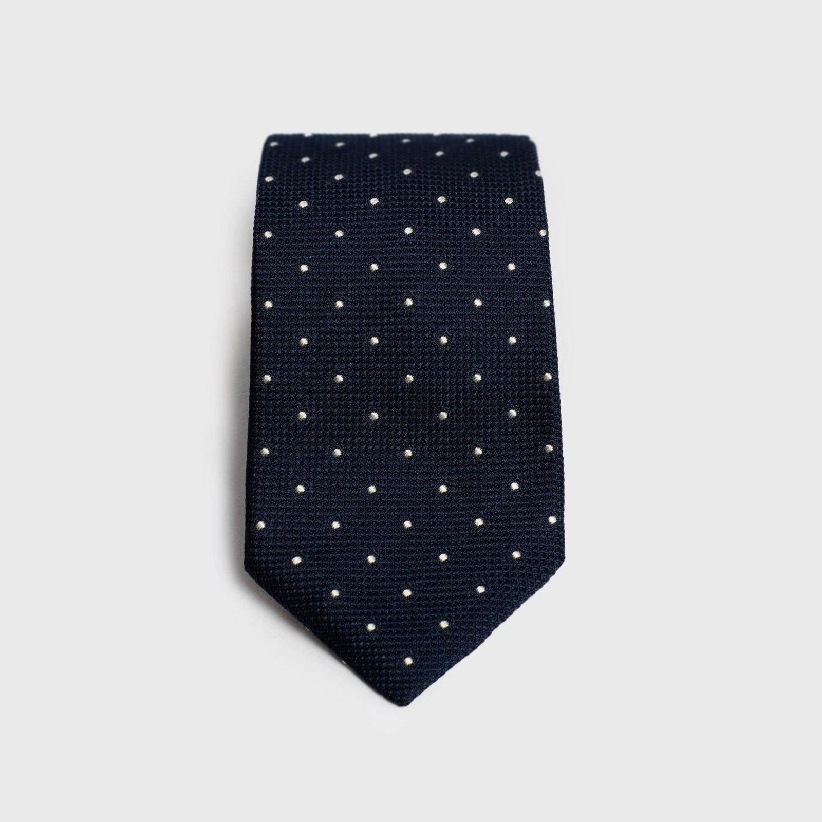 Navy dotted grenadine tie with a textured finish, folded for display.