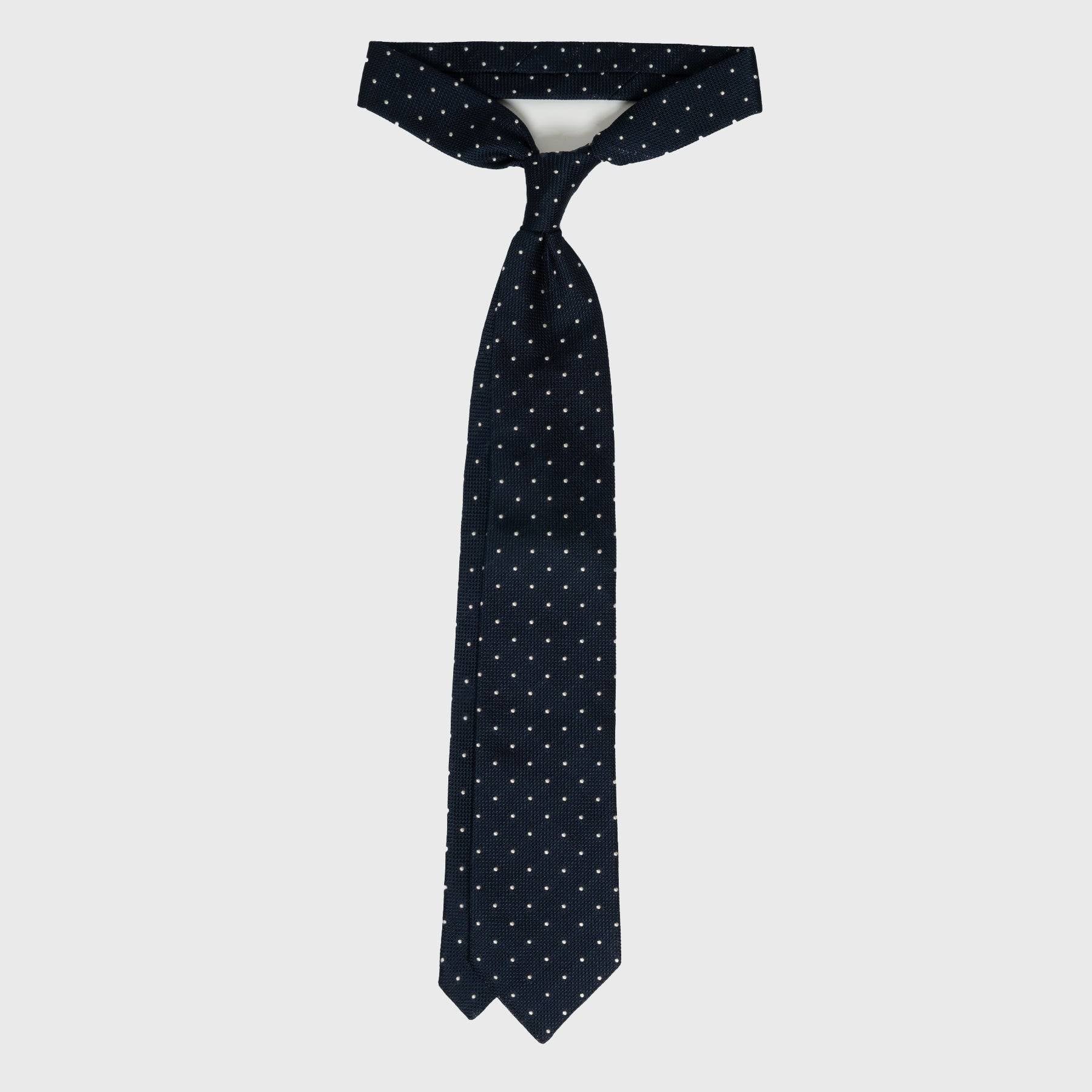Navy dotted grenadine tie tied in a classic knot, showcasing its length.