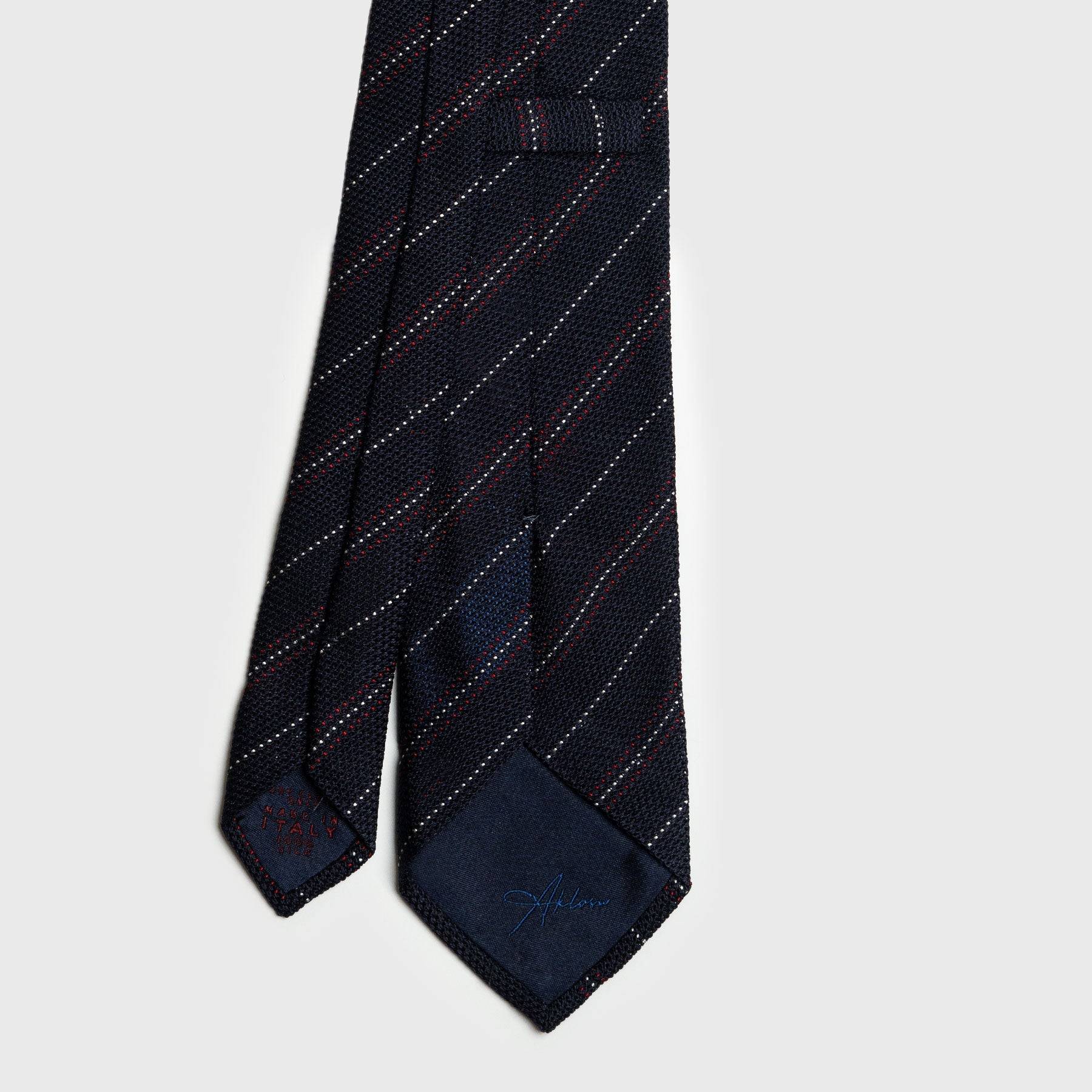 Back view of red and white striped blue grenadine tie with detailed stitching.