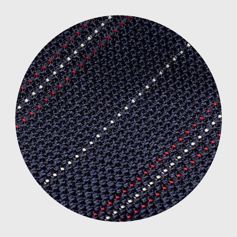 Close-up of red and white striped blue grenadine tie's textured silk fabric.