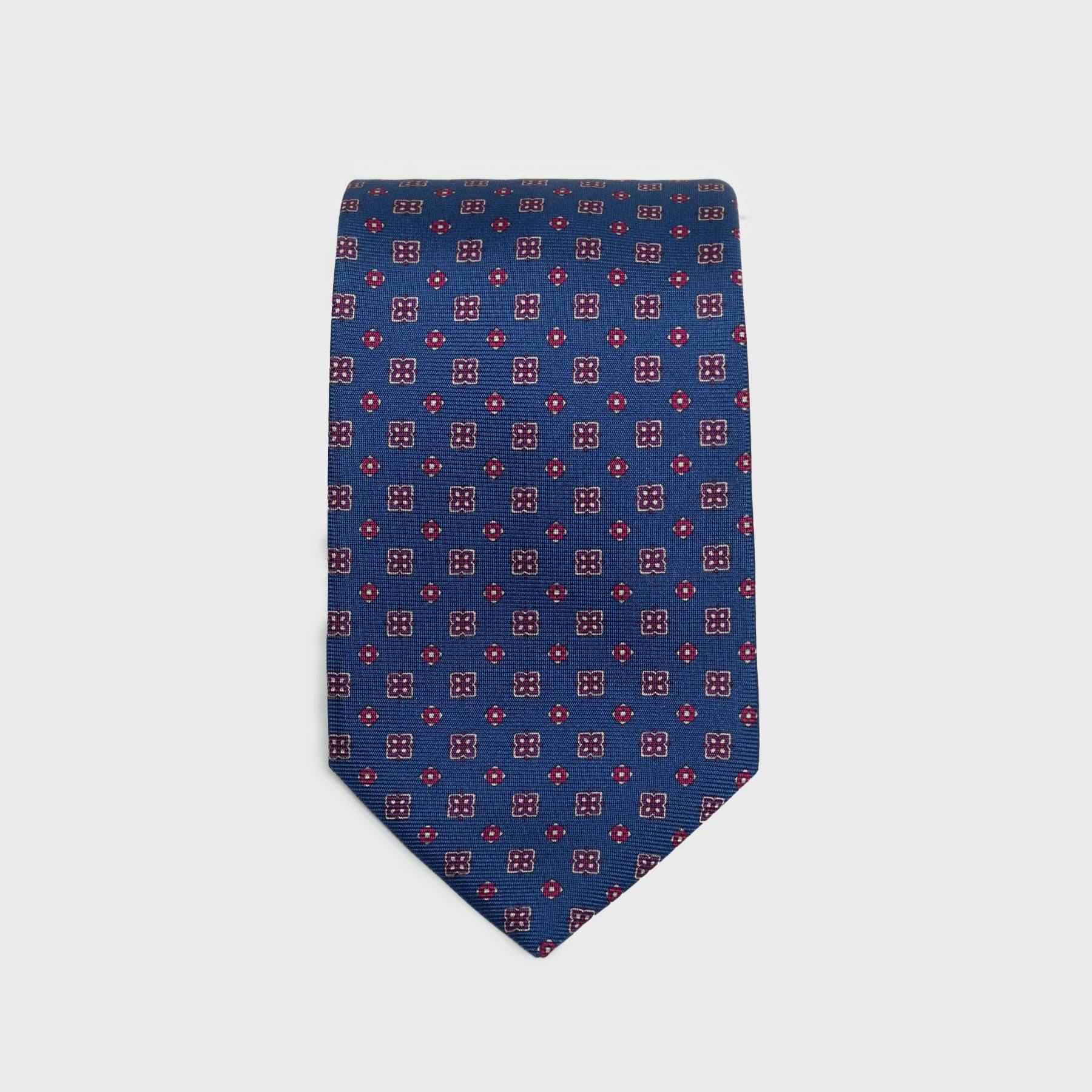 Royal blue silk tie with red and white floral foulard print, folded neatly.