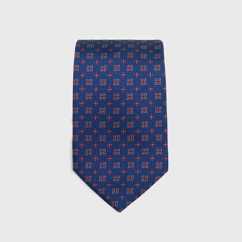 Royal blue silk tie with red and white floral foulard print, folded neatly.