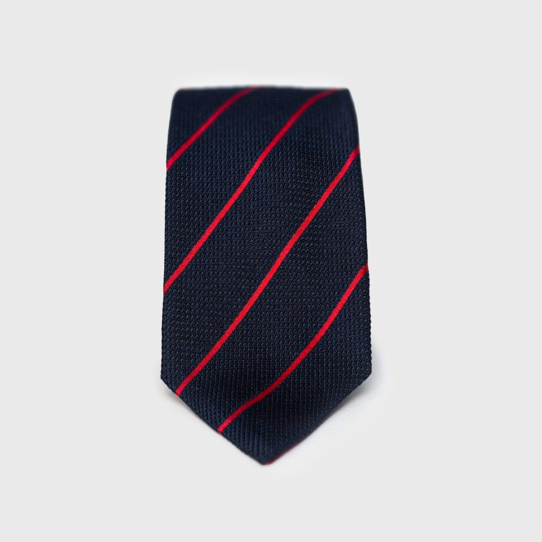 Close-up of smooth red striped blue grenadine tie with elegant texture.
