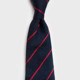 Knotted smooth red striped blue grenadine tie highlighting its refined design.