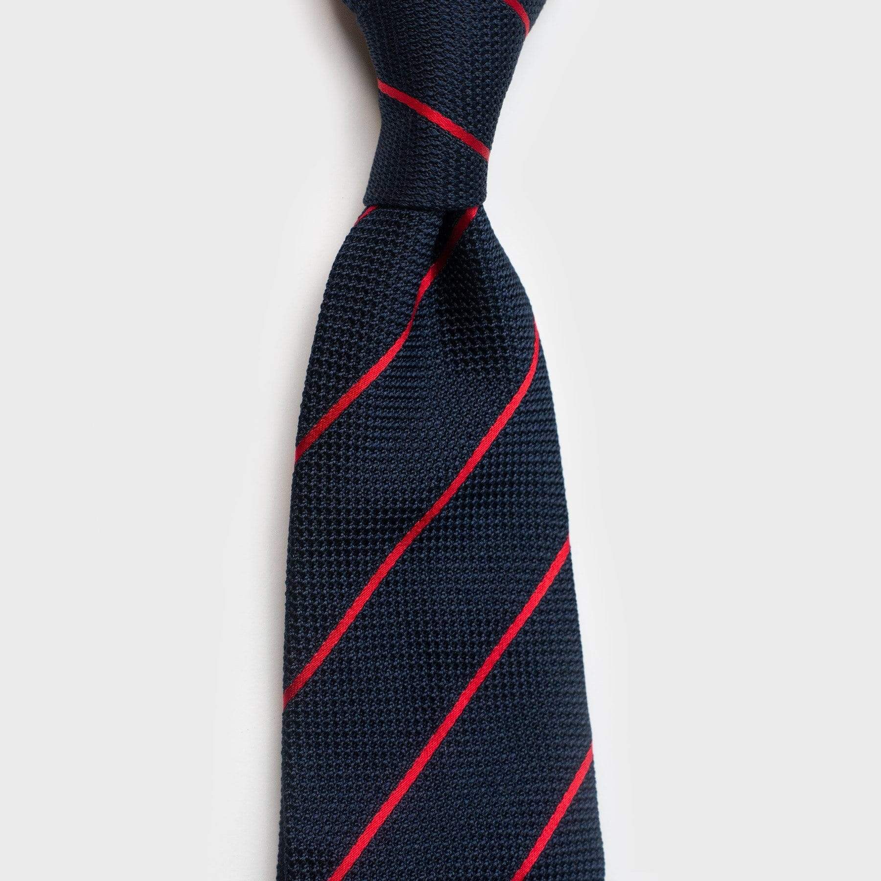 Knotted smooth red striped blue grenadine tie highlighting its refined design.
