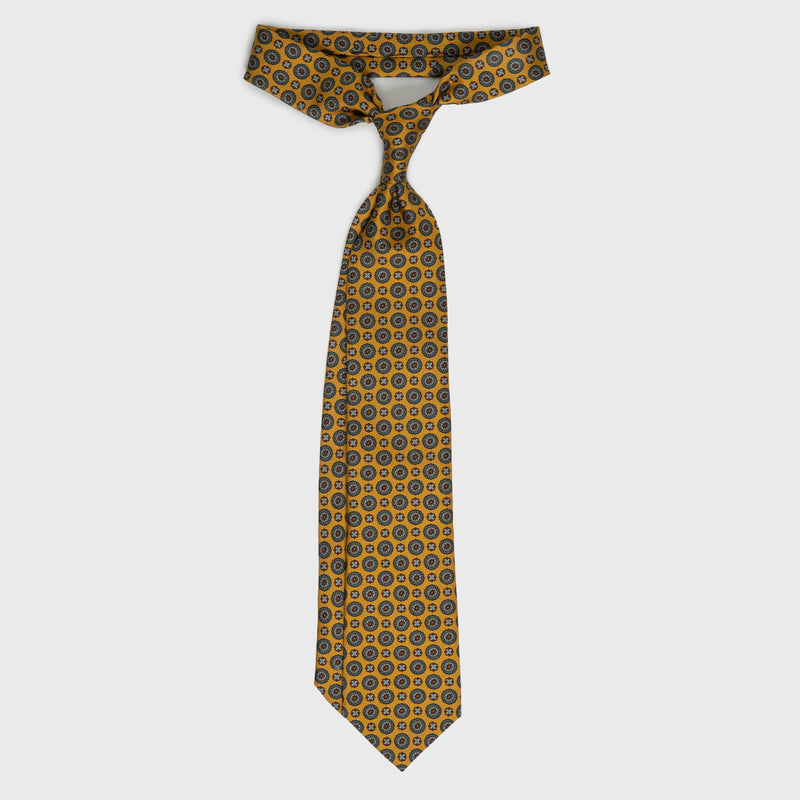 Golden yellow medallion foulard printed silk tie displayed untied.