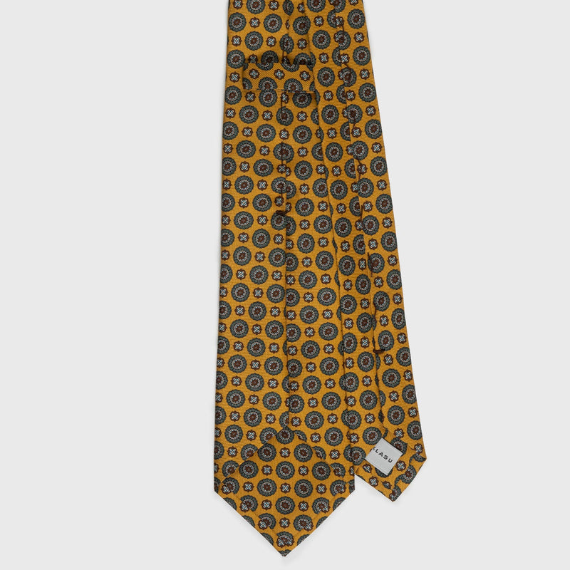 Back view of golden yellow medallion foulard printed silk tie with label.