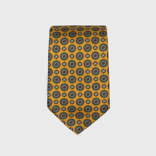 Golden yellow silk tie with medallion foulard print, folded neatly.