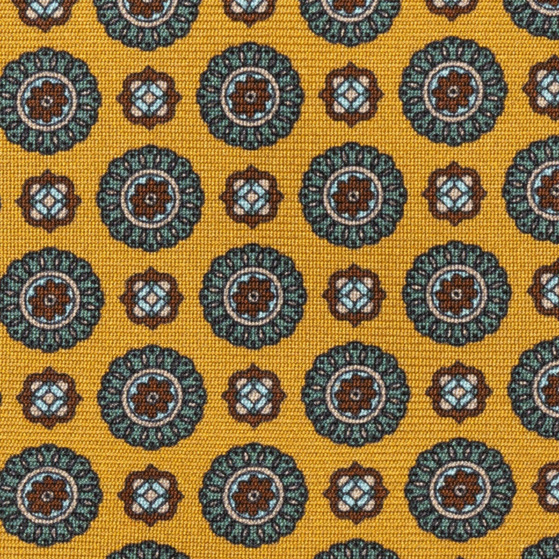 Close-up of medallion foulard pattern on golden yellow silk tie.