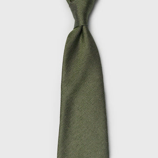 Sage green silk tie tied in a classic knot, highlighting its textured pattern.